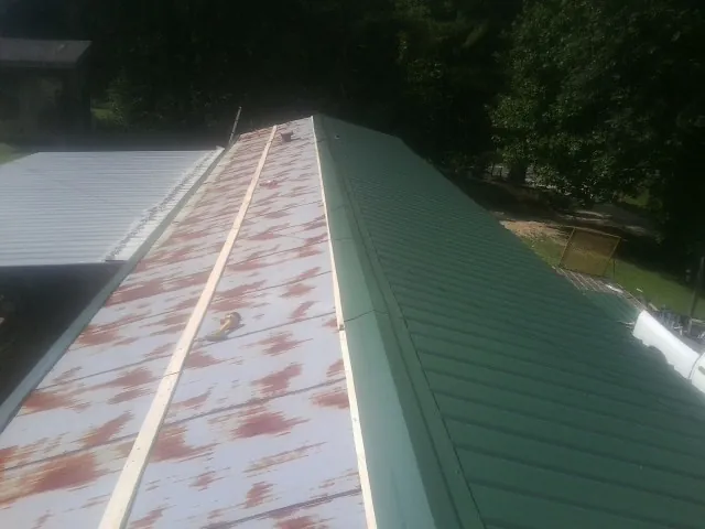 Old rusted panels beside newly installed green metal roofing — Wind Damage Roof Repair by Roofing Brothers in Sevier