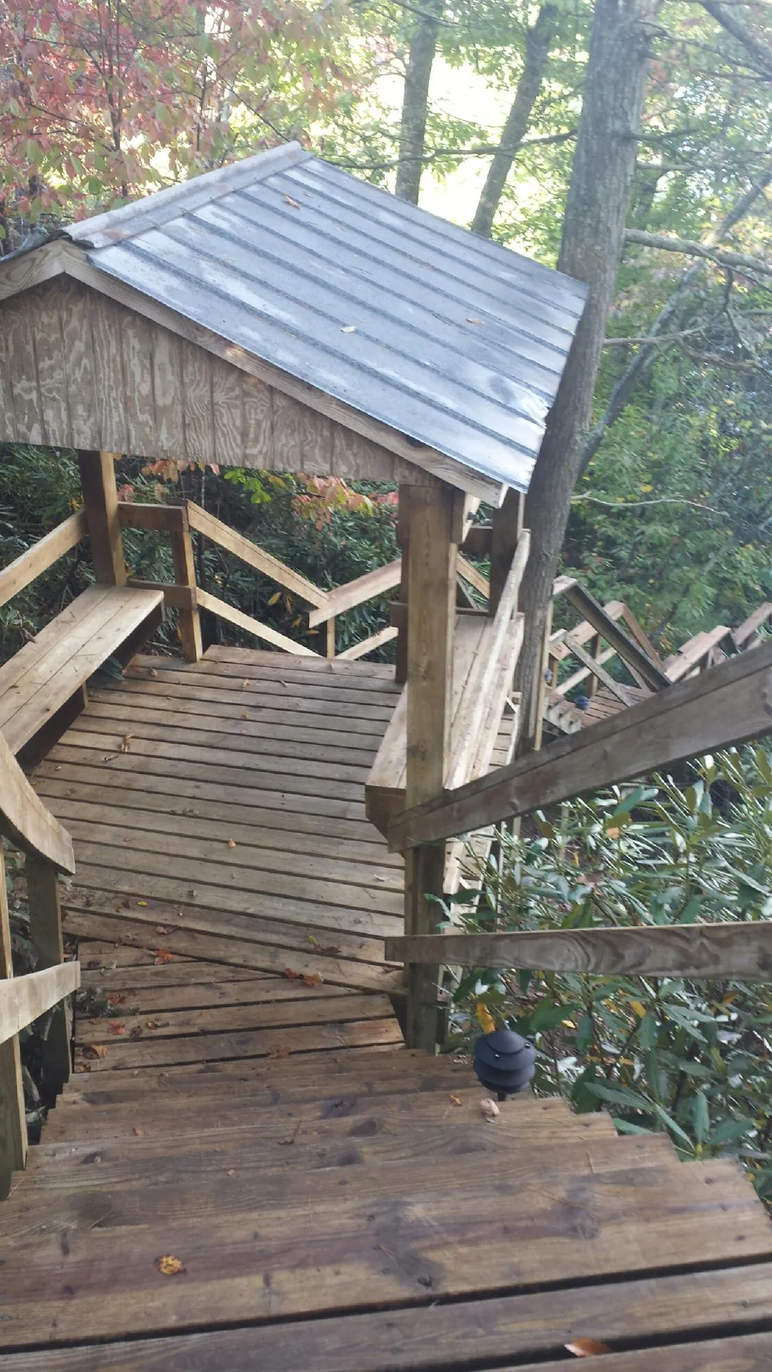 Metal roofed shelter over wooden steps on a wooded walkway — Skylight Repair & Installation work by our crew in Sevier