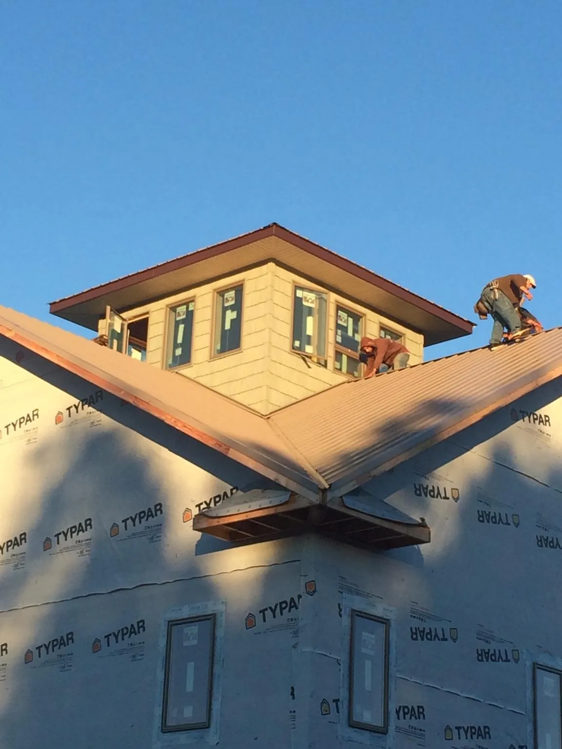 Roofers working around a rooftop cupola on a new metal roof at sunset — Roof Waterproofing in Sevier by Roofing Brothers